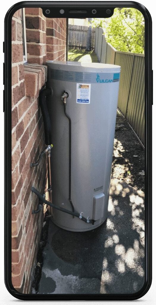 A smartphone screen displaying a photo of a grey Vulcan electric hot water storage tank