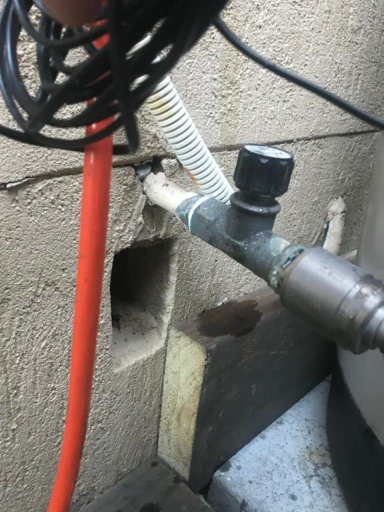 A close-up view of an outdoor plumbing setup against a textured wall