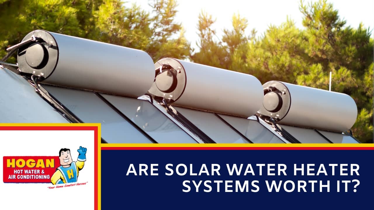 A three white horizontal storage tanks and flat solar collector panels installed on a rooftop