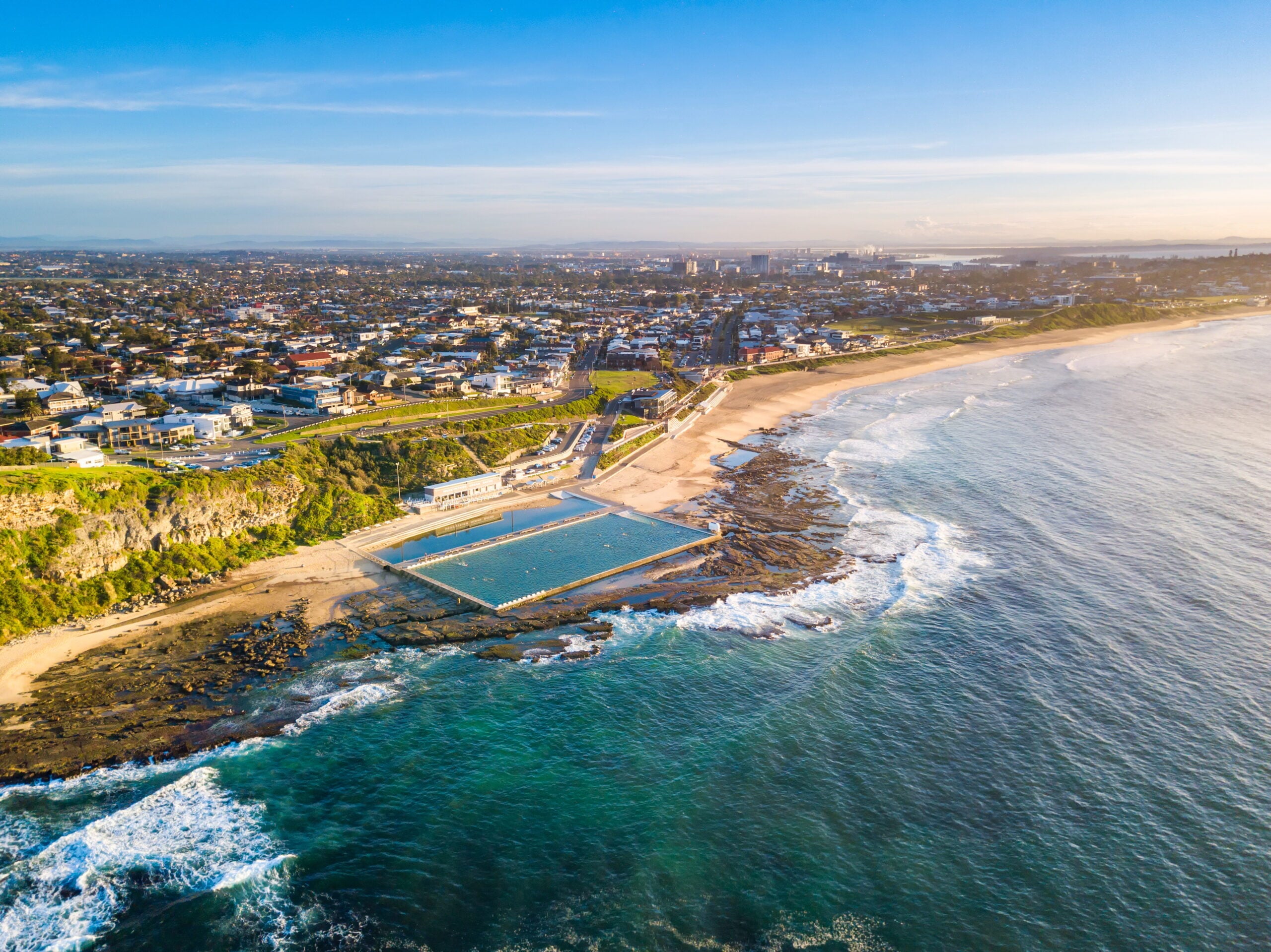 A coastal city featuring a large ocean pool built into the rocky shoreline of Merewether