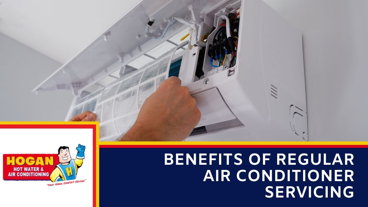 A technician's hands removing or installing a clean mesh filter inside an open wall-mounted split-system air conditioning unit.