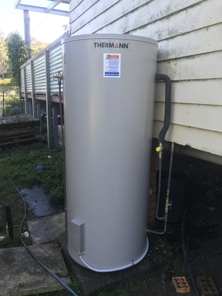 Thermann outdoor electric hot water system tank installed beside a house.