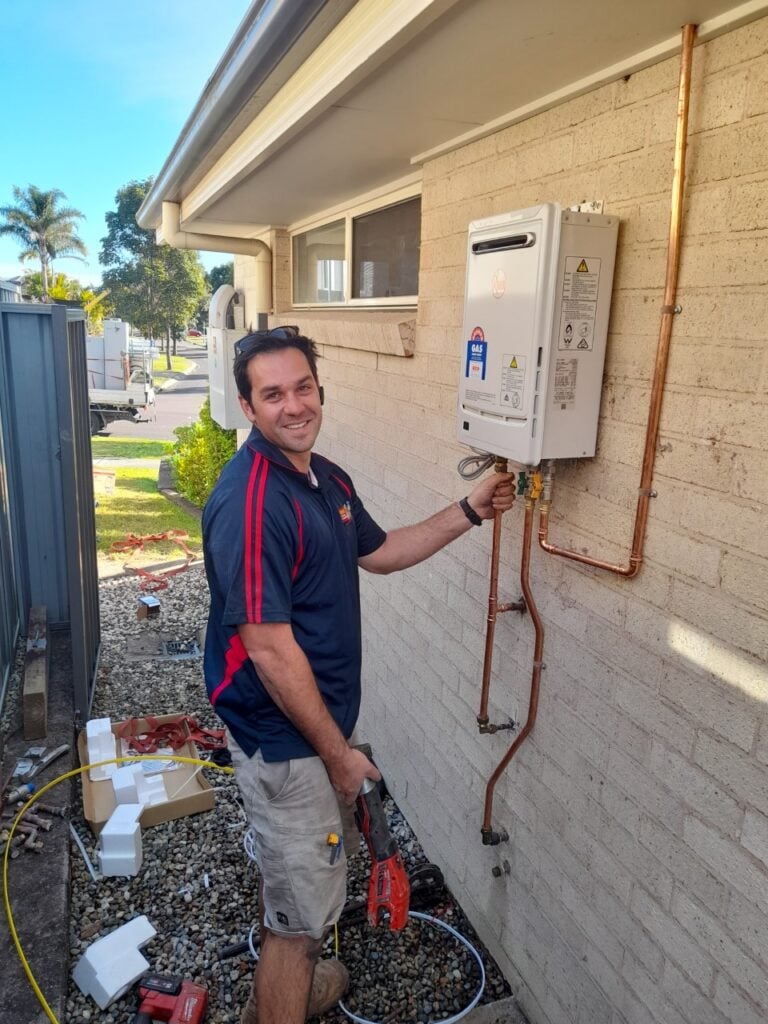 Licensed plumber installing a Rheem Metro 26 six star continuous flow gas hot water system outside a home in Newcastle, NSW