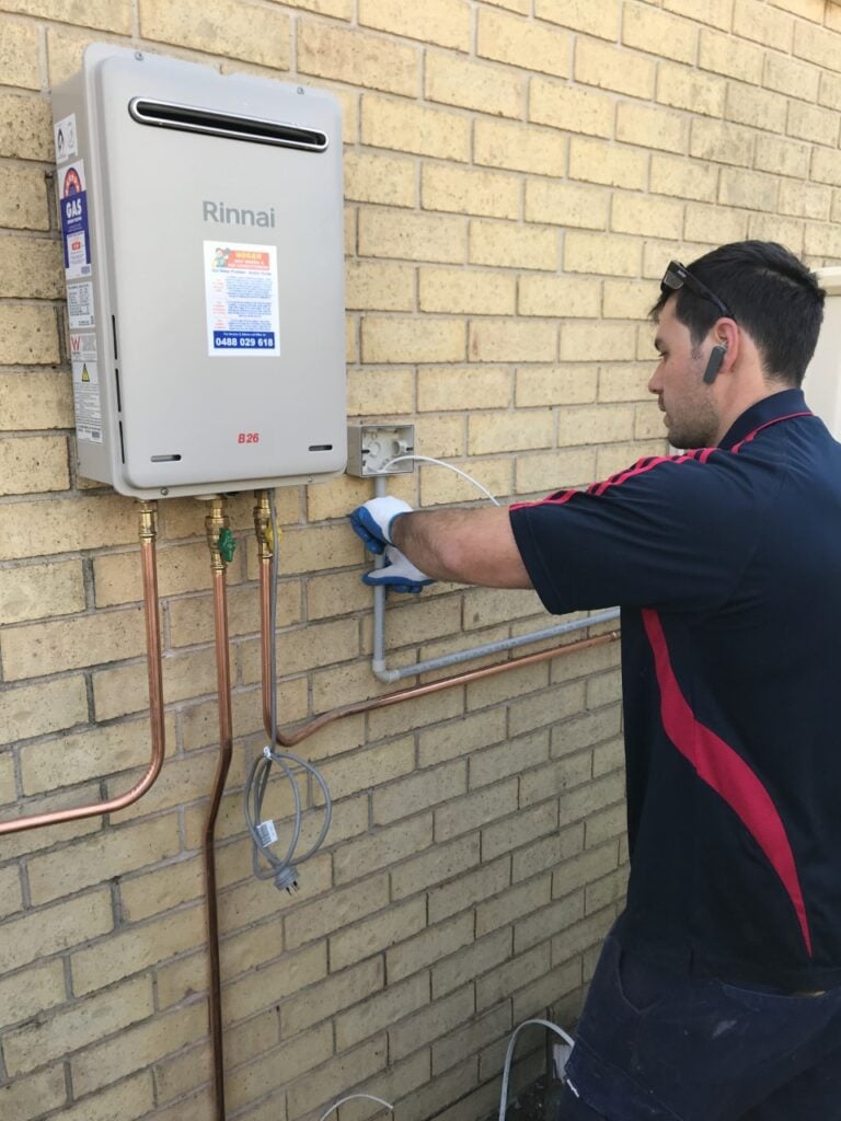 A technician from Hogan Hot Water performing an installation on a Rinnai B26 continuous flow gas hot water system.