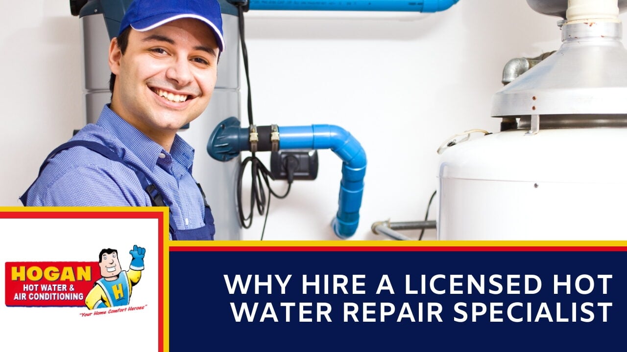 A plumber in a blue cap and overalls standing next to hot water storage tanks and blue PVC piping.