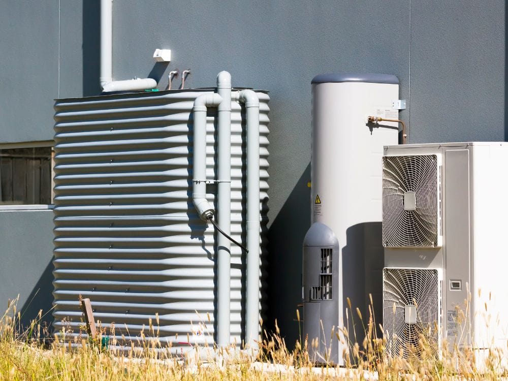 A corrugated metal rainwater tank and an outdoor heat pump system.