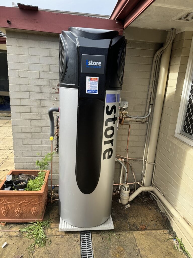 iStore air-to-energy heat pump water heater system installed outdoors on a paved patio.