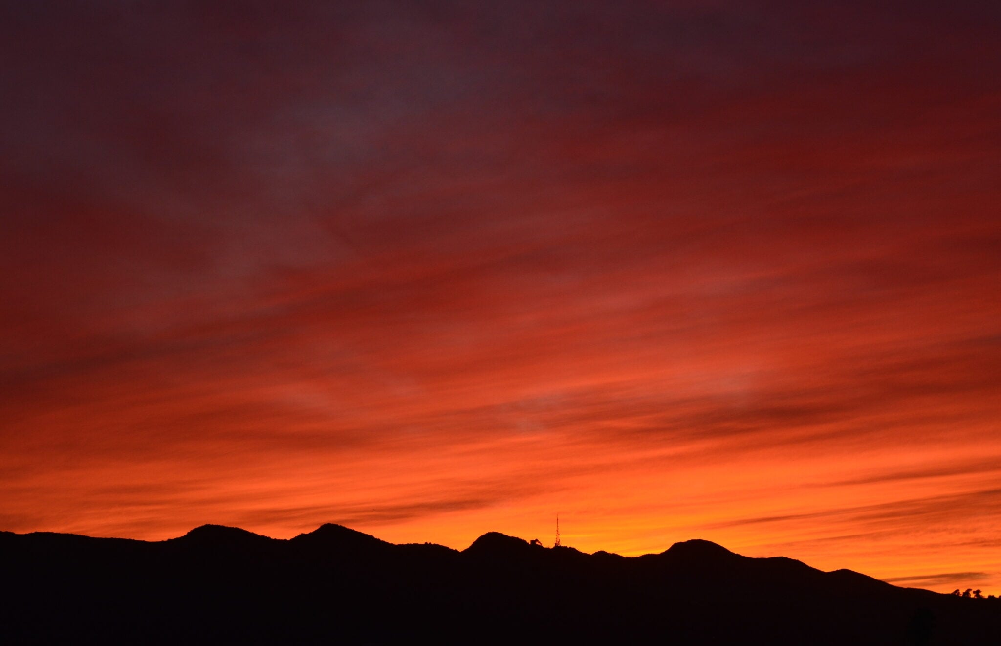 A silhouette of a mountain range against a vibrant sunset