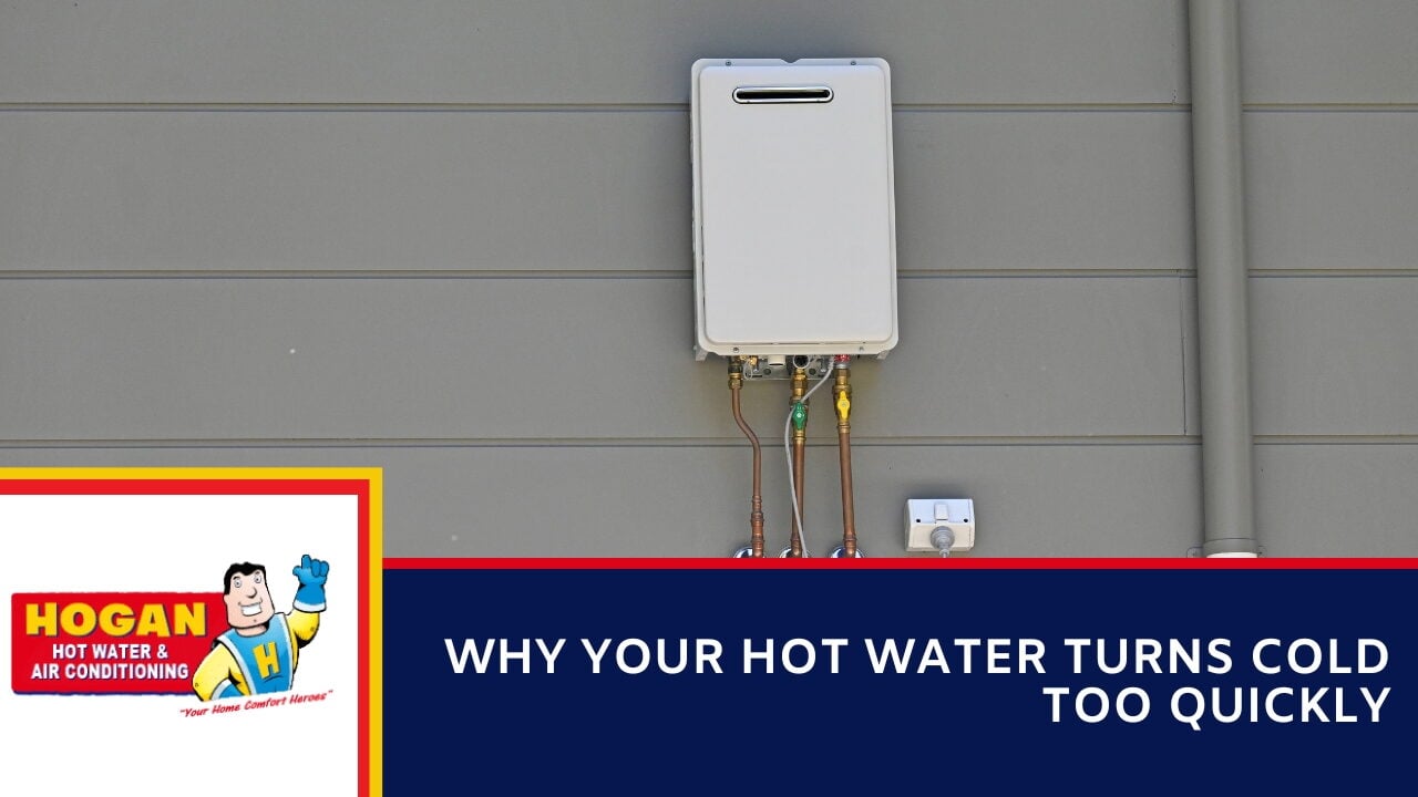 An outdoor tankless water heater mounted on a grey wall.