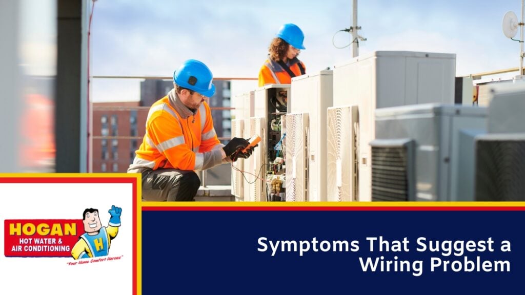 Two Aircon technicians in blue hard hats and orange safety vests inspecting outdoor air conditioning units on a rooftop