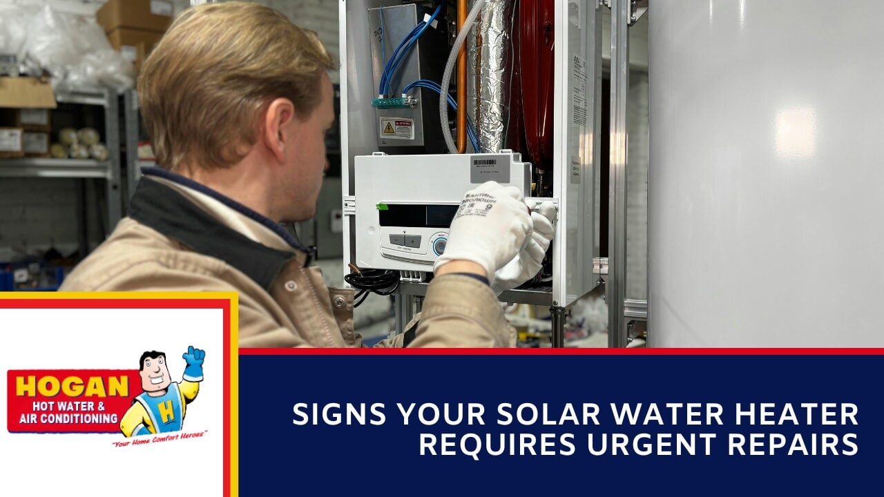 A technician from behind wearing work gloves while servicing the open control panel of a water heating system.