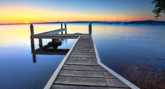 Hot Water Belmont NSW A wooden jetty extending into a calm lake in Belmont