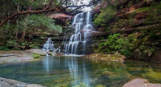 Hot Water Installation and Maintenance Kariong A long-exposure view of a multi-tiered waterfall cascading down a red rock face into a clear pool of Kariong
