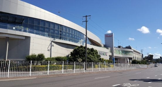 Hot Water Installation and Maintenance Kotara A large, modern Westfield shopping centre building with curved grey facades and a glass-enclosed upper level.