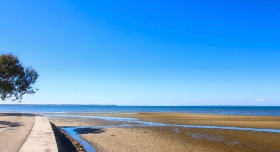 Hot Water Installation and Maintenance Sandgate A coastal walkway bordering a sandy beach at low tide