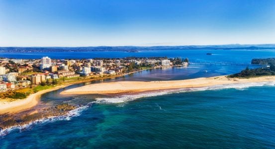 A vibrant coastal city where a turquoise ocean meets a calm blue lagoon in Tuggerah