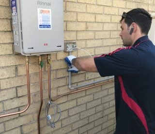 A technician from Hogan Hot Water performing an installation on a Rinnai B26 continuous flow gas hot water system.