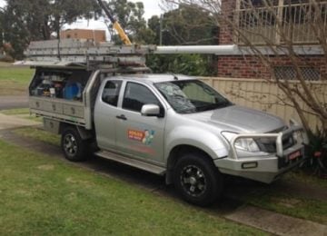 A silver Hogan Hot Water service truck parked on a residential driveway